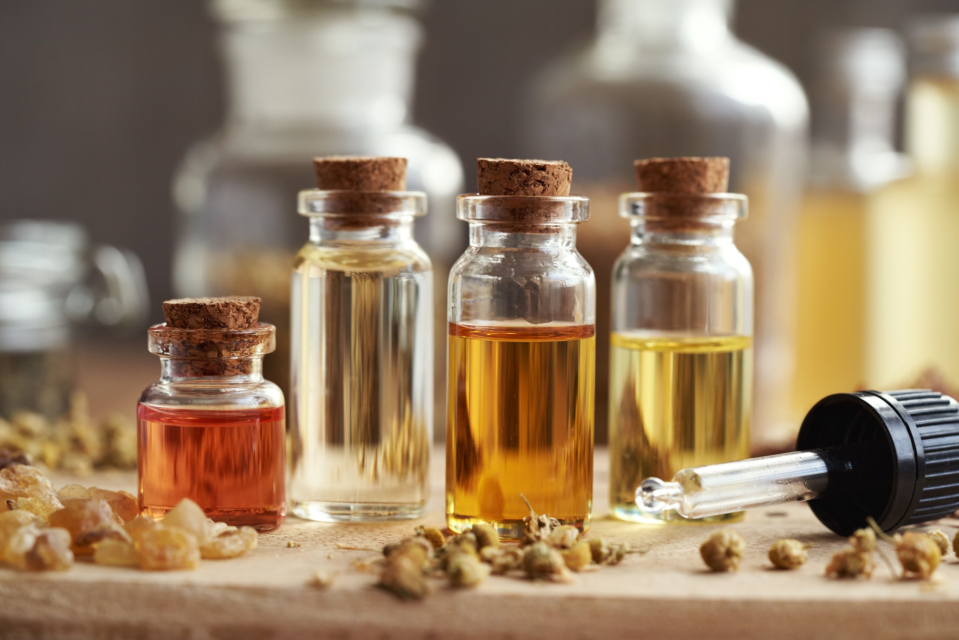 Four bottles of aromatherapy essential oils with frankincense resin and dry herbs